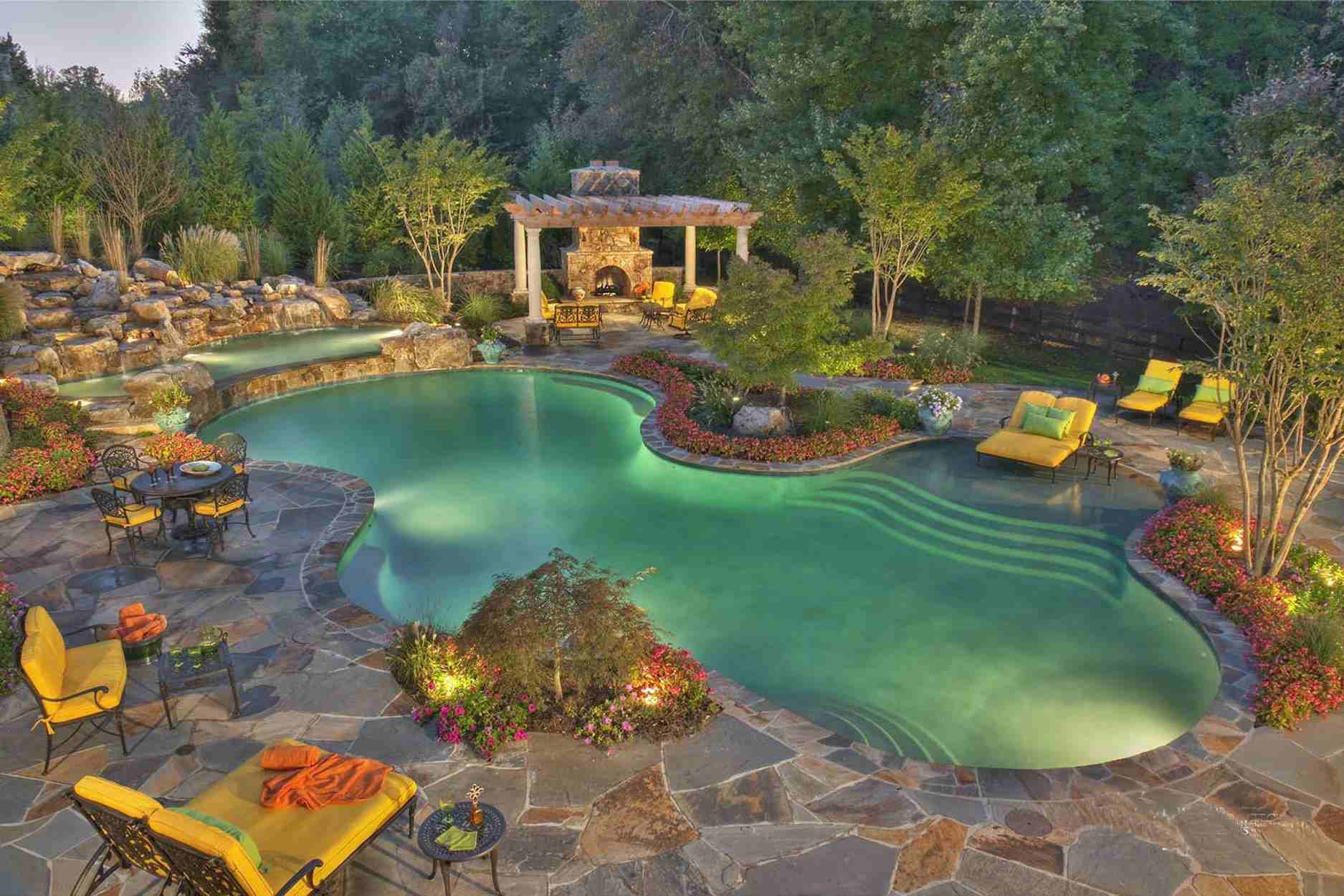 Piscine méditerranéenne avec lumières de piscine et chaises de patio rembourrées jaunes.