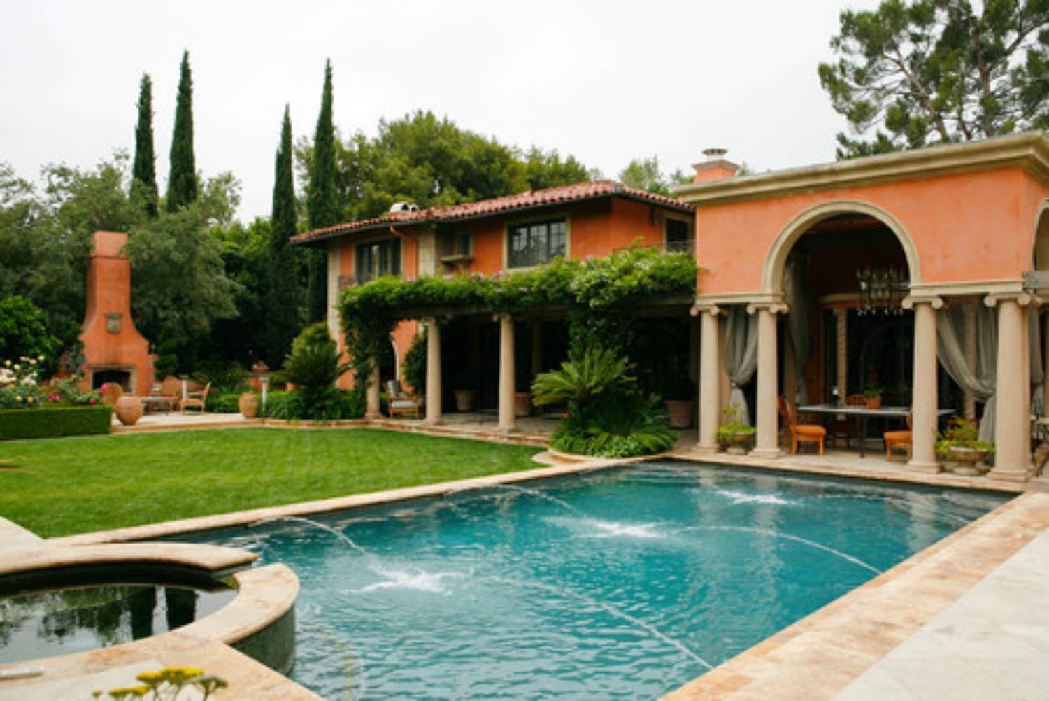 Piscine méditerranéenne avec patio orné de piliers et cheminée extérieure.