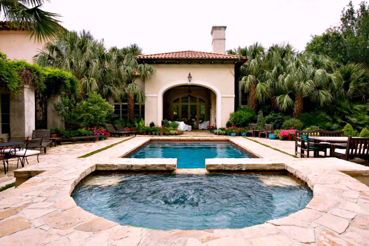 Piscine de style méditerranéen avec allée en pierre et grands arbres.